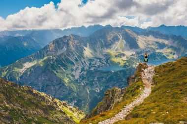 kadın cliff üzerinde duruyor ve dağlar başında görünüyor