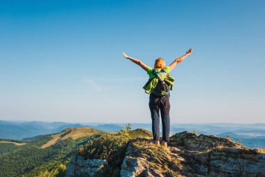 kadın cliff üzerinde duruyor ve dağlar başında görünüyor