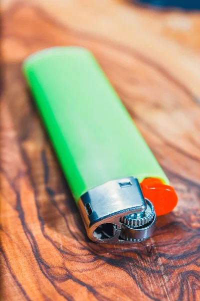 Isqueiro de gás plástico verde no fundo de madeira de oliveira, close-up — Fotografia de Stock