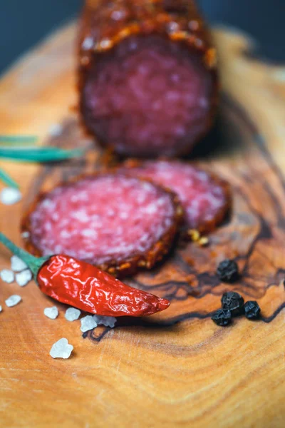 Salame seco crostado em pimenta vermelha moída em fundo escuro — Fotografia de Stock