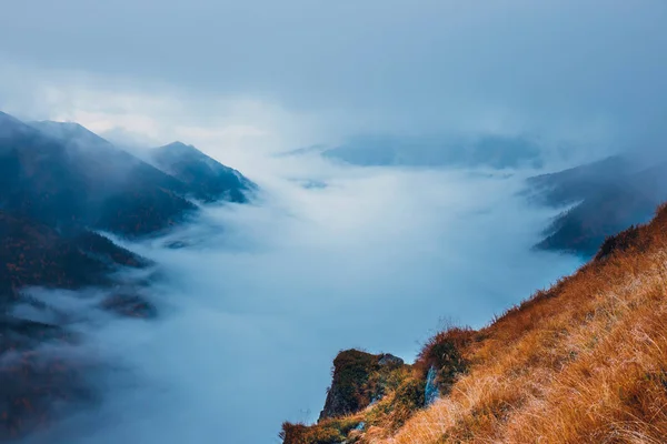 foggy mountain landscape with clouds above the peaks