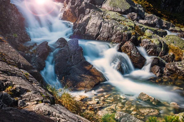 Vackra vattenfall i bergen med strålar solen skiner genom träden — Stockfoto