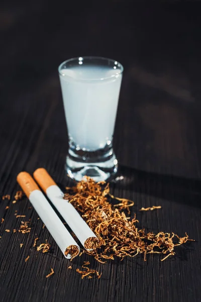 Cigarette et tabac faits à la main avec un verre de vodka en arrière-plan — Photo