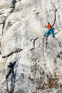 Polonya, Podlesice - 04 Şubat 2017: Yan görünüm yetişkin erkek kaya tırmanışçısı zavallı kabartmalı dikey düz duvarda. Gora Zborow dağcılar arasında çok popüler bir yer 