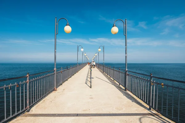 Miedzyzdroje, Polonia - 09 de abril de 2016: Gente caminando sobre un muelle de concreto en Miedzyzdroje. Ciudad y un balneario en Polonia en la isla de Wolin — Foto de Stock