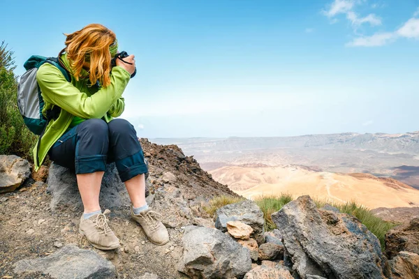 Jonge vrouw bewondert uitzicht op de prachtige bergen en neemt foto 's — Stockfoto