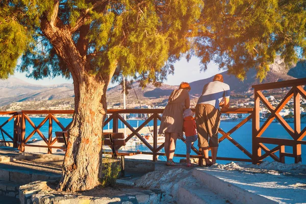 Hersonissos, Crète, 13 juin 2017 - Un couple inconnu avec un petit enfant admire le coucher de soleil dans la ville de Hersonissos, Crète, Grèce — Photo