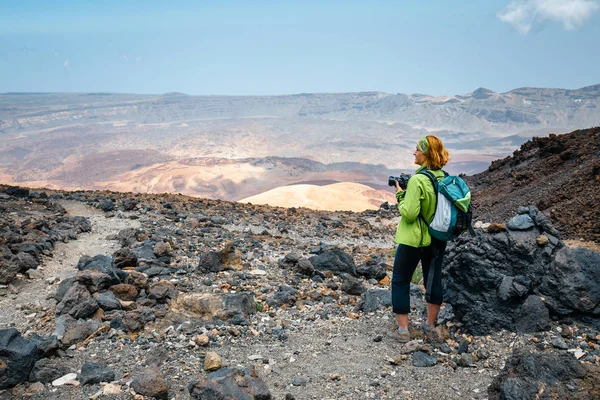 Jonge vrouw bewondert uitzicht op de prachtige bergen en neemt foto 's — Stockfoto