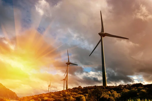 Ветряные мельницы для производства электроэнергии в горах на закате — стоковое фото