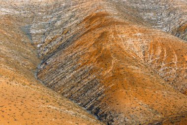 Fuerteventura Adası 'nda gün batımında tepelerin manzarası. Baskın renk kırmızı ve turuncu.