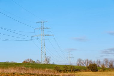 Çelik yüksek voltaj direkleri ve mavi gökyüzü ve kırsal alanlarda bulunan elektrik telleri..