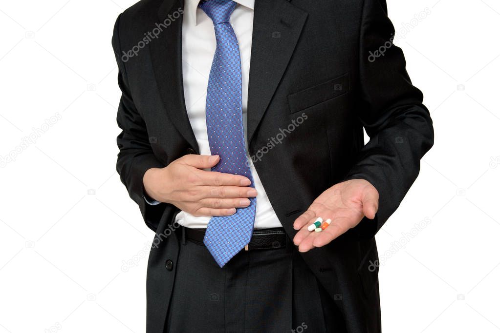 Businessman holding pill in hand and holding abdominal pain.