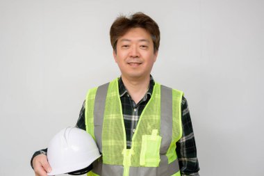 Açık yeşil iş yeleği ve beyaz şapkalı Asyalı orta yaşlı bir adam..