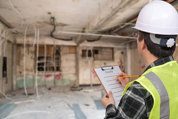 Un trabajador asiático de mediana edad revisando algo con una lista de verificación en su mano . — Foto de Stock