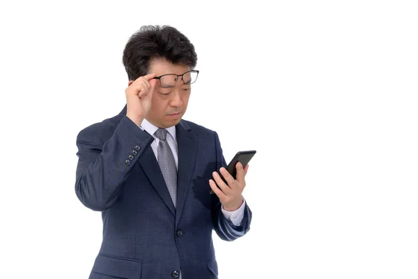 アジアのビジネスマンは携帯電話で何かを読もうとしている。貧しい光景や偏見や近視は. — ストック写真