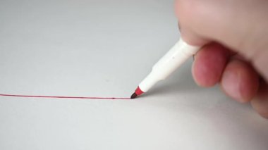 Ağır çekim. Kırmızı kalemle beyaz çizgili kağıda kırmızı çizgi çiziyorum. Eğitim kavramı.