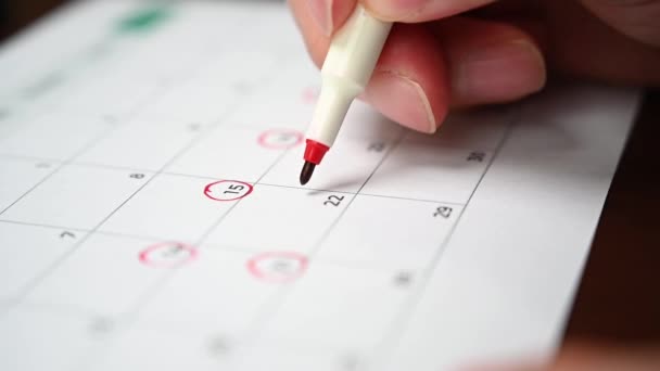 Câmara lenta. A mão de um homem segurando uma caneta na mão e gravando seu cronograma em um calendário de mesa . — Vídeo de Stock