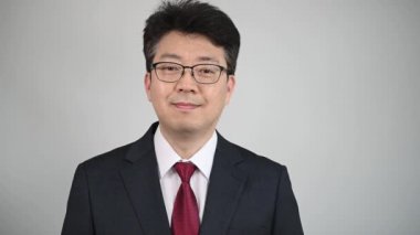 Asyalı erkek işadamı öne bakıyor ve gülümsüyor..