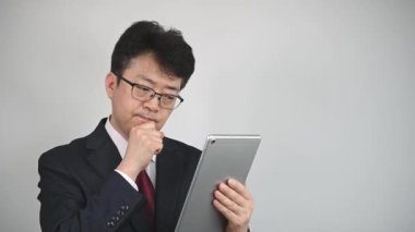 Bilgi aramak ya da iletişim kurmak için tablet kullanan Asyalı bir işadamı.