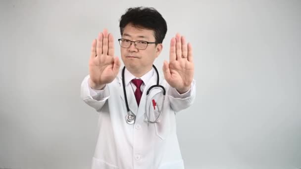 中年のアジア人医師が手を挙げて彼の不承認を表明します — ストック動画