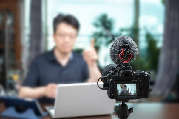 Online ders konsepti. Asyalı orta yaşlı bir adam evde online konferans veriyor. Bulanık arkaplan