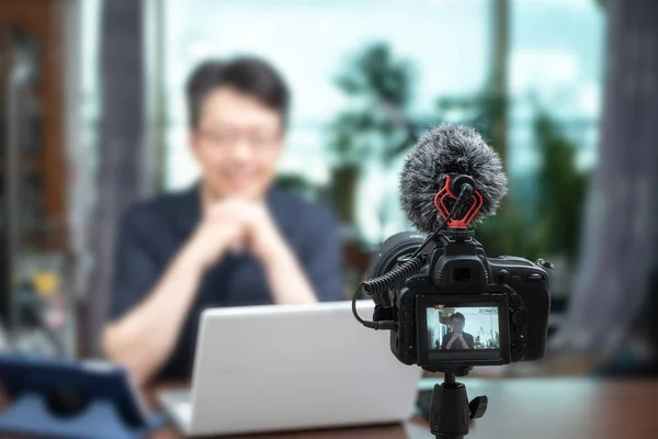 Online ders konsepti. Asyalı orta yaşlı bir adam evde online konferans veriyor. Bulanık arkaplan