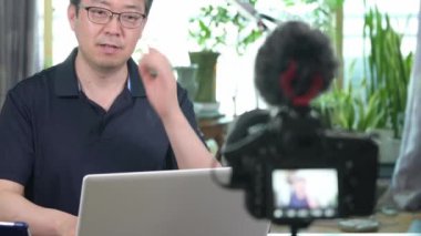 Online ders konsepti. Asyalı orta yaşlı bir adam evde online konferans veriyor. Uzaklaştır.