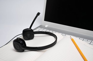 Çevrimiçi öğrenme kavramı. Dizüstü bilgisayarın klavyesinde çizgili bir defter ve sarı bir kalem var.