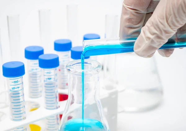 Una mano de los investigadores sosteniendo un tubo de ensayo que contiene líquido azul . — Foto de Stock
