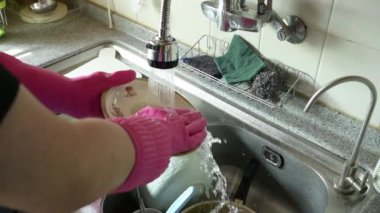 Ağır çekim. Ev mutfağında yemekten sonra bulaşık yıkayan birinin elleri..