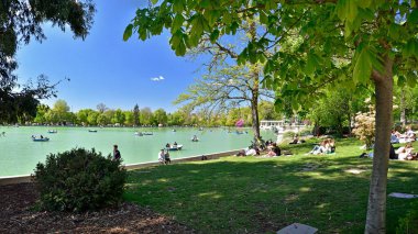 Madrid / İspanya - 12 Nisan 2019 - Gençler İspanya 'nın başkenti Madrid' in ana parkı olan Jardines del Buen Retiro 'da güneşleniyorlar..