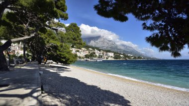 BRELA, CROATIA - 3 Mayıs 2019 - Brela limanındaki sahil yolu. Hırvatistan 'daki Makarska Rivierası güzel çakıl taşı plajları ve kristal berrak suyuyla ünlüdür.