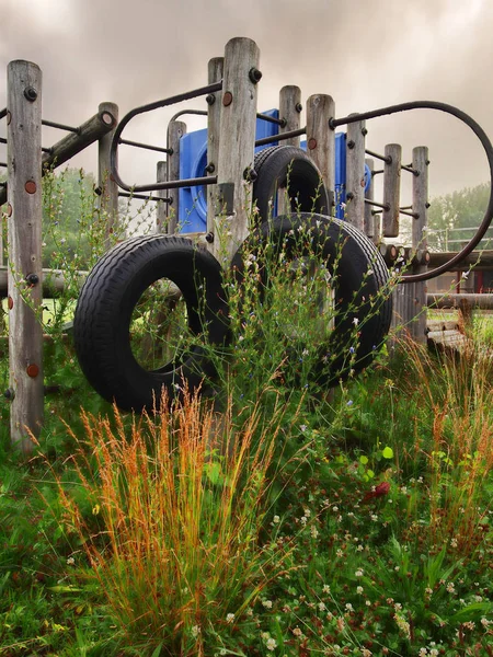 Parque infantil abandonado com vegetação sobrecultivada — Fotografia de Stock