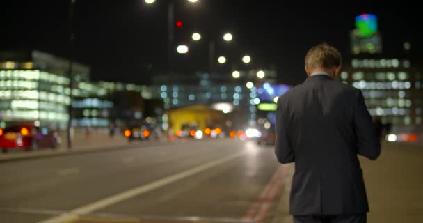 Strzał czerwony autobus Londyn przechodzący obok mężczyzna nadaje się na London Bridge — Wideo stockowe