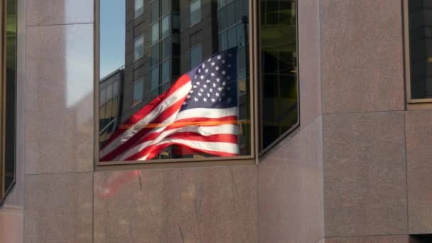 Een schot van de reflectie van een vlag van de Verenigde Staten in een venster — Stockvideo