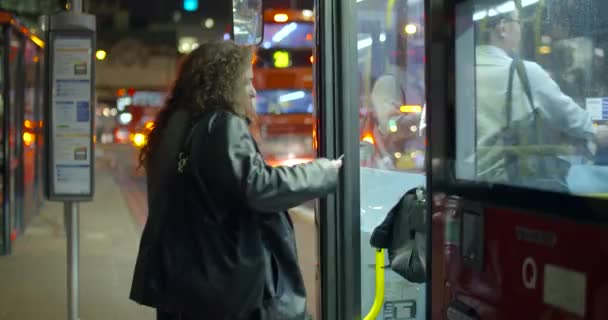 一个固定的拍摄的人登上一辆红色的伦敦巴士在晚上 — 图库视频影像