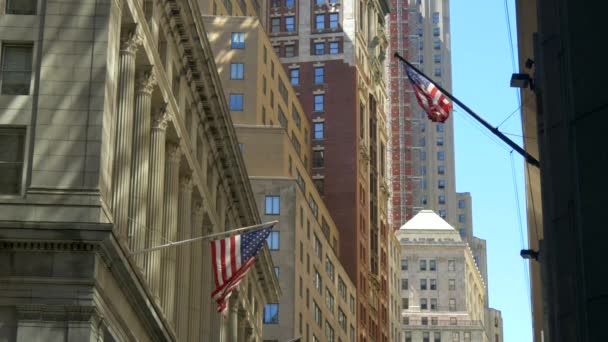 Um tiro estacionário de bandeiras dos EUA voando em Wall Street — Vídeo de Stock