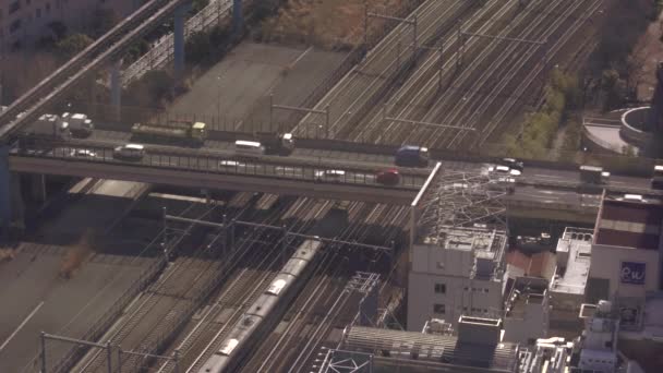 Tren en Tokio pasando por debajo de un puente de autopista ocupado — Vídeos de Stock