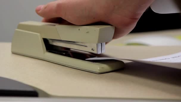 A medium shot of a tan office stapler being used to staple papers in an office — Stock Video