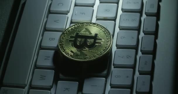En roterande skott av en casascius bitcoin på en vit dator tangentbord — Stockvideo
