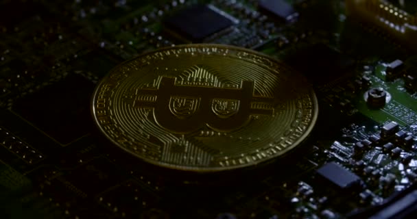 Shadowy rotating shot of a bitcoin on an electronic circuit board — Stock Video