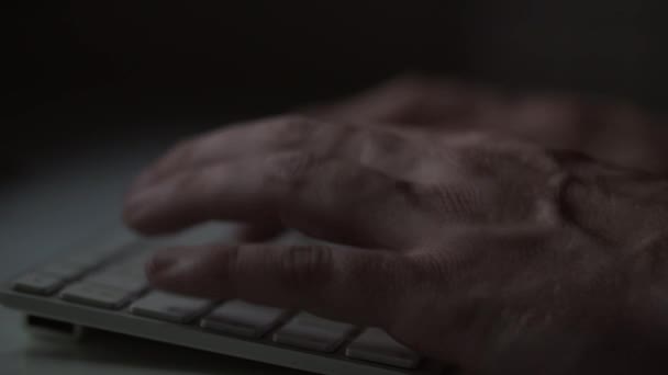 Zijaanzicht van een man te typen op een toetsenbord van de computer in een donkere kamer — Stockvideo