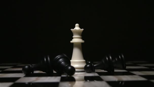 White queen piece surrounded by fallen black pawns — Stock Video