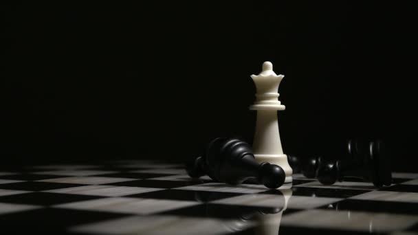 Reina blanca rodeada de peones caídos, sobre un tablero de ajedrez de mármol — Vídeo de stock