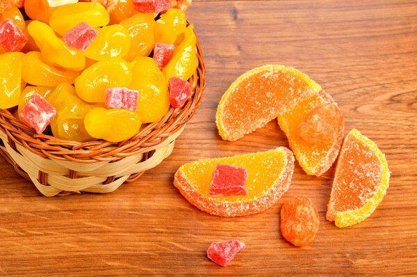 candies and jellies in basket on wood