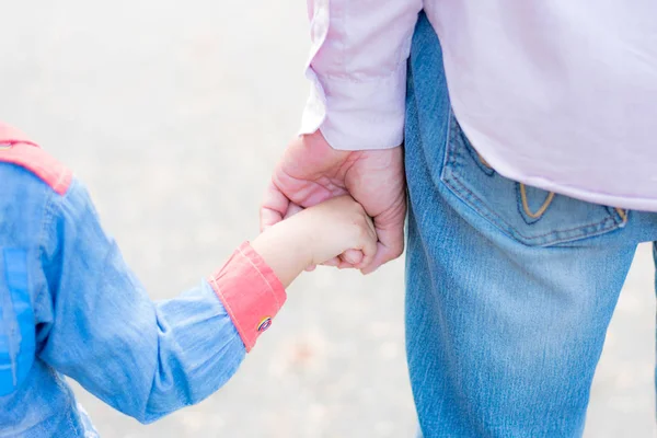 Mutlu bir geçmişi olan çocuğun elini tutan ebeveyn.