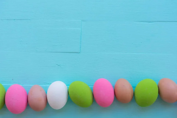 Sp ile mavi pastel renk ahşap arka plan üzerinde renkli Paskalya yortusu yumurta