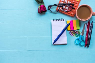 Ofis masasında malzeme, kahve fincanı ve çiçek var. Üst görünüm