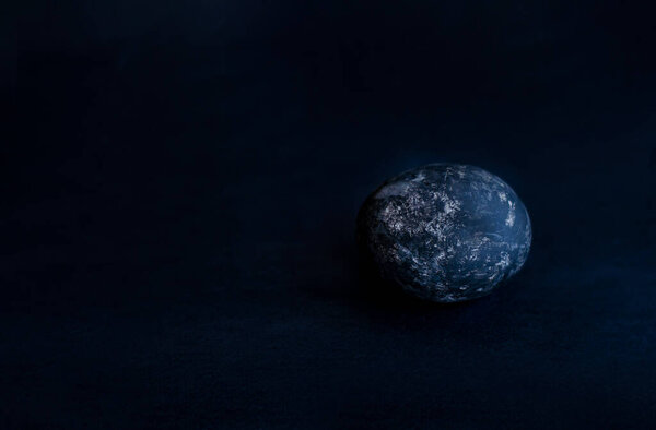 on a black background an egg of black color asymmetrically placed egg