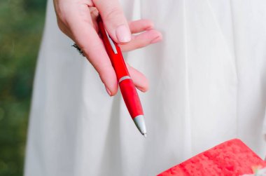 Kızlar kırmızı renkli kitapları bir el kitabında tutarlar. Çiçekler açan bahar yaprakları. Beyaz kırmızı.